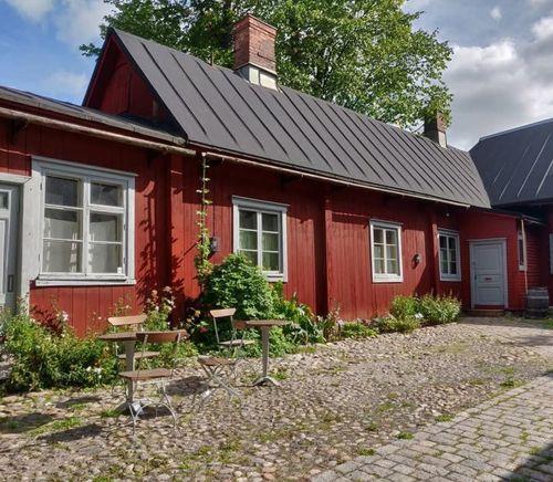 The courtyard of the Pharmacy Museum and the Qwensel House. Red wooden buildings with white window frames.