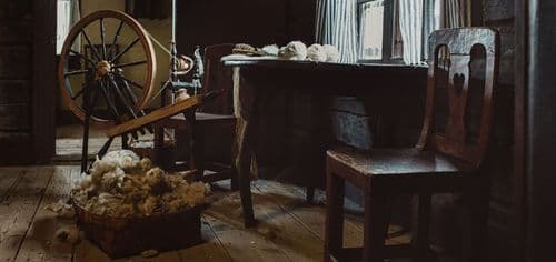 a spinning wheel and old furniture in an old house.